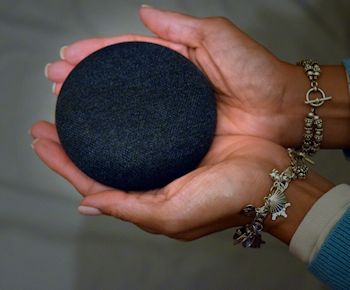 Google Home device cupped in the hands of an off camera person.