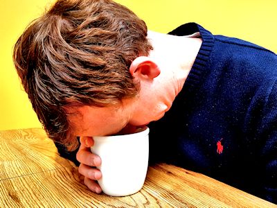 Man falling asleep on coffee mug thinking about payment processors